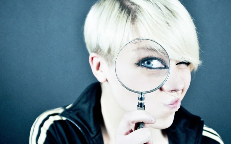 woman holding magnifying glass to her eye